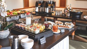 Un bufé con una variedad de alimentos, entre ellos frutas, postres y bebidas.