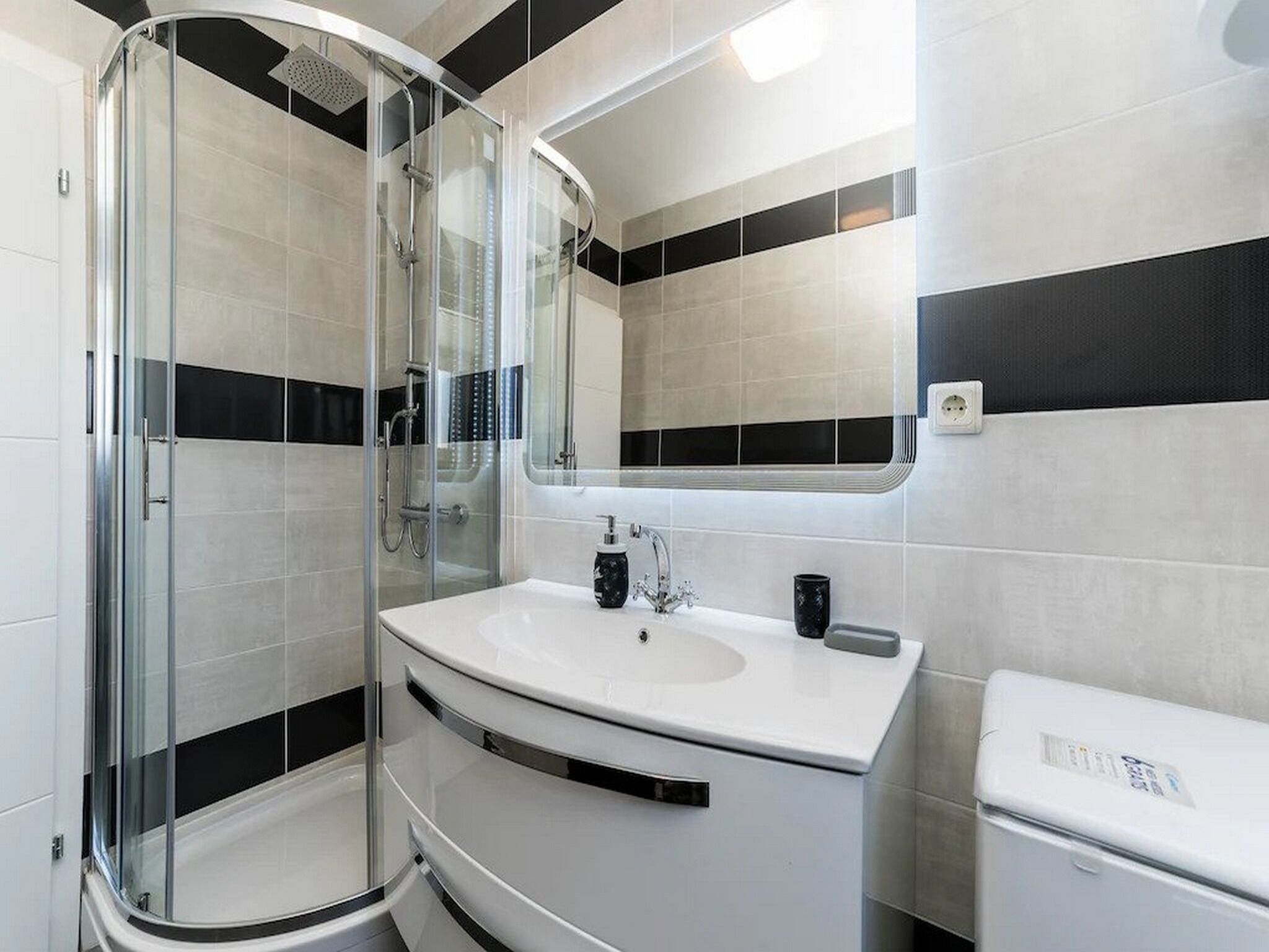 Une salle de bain moderne avec une douche à parois de verre, un lavabo blanc et des toilettes.