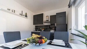 Une cuisine moderne avec des meubles de couleur sombre et un coin repas avec une table dressée pour deux personnes.