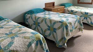 A room with two beds, each with a quilted bedspread and a wooden headboard. - Cottage on The Lake (Redfield)