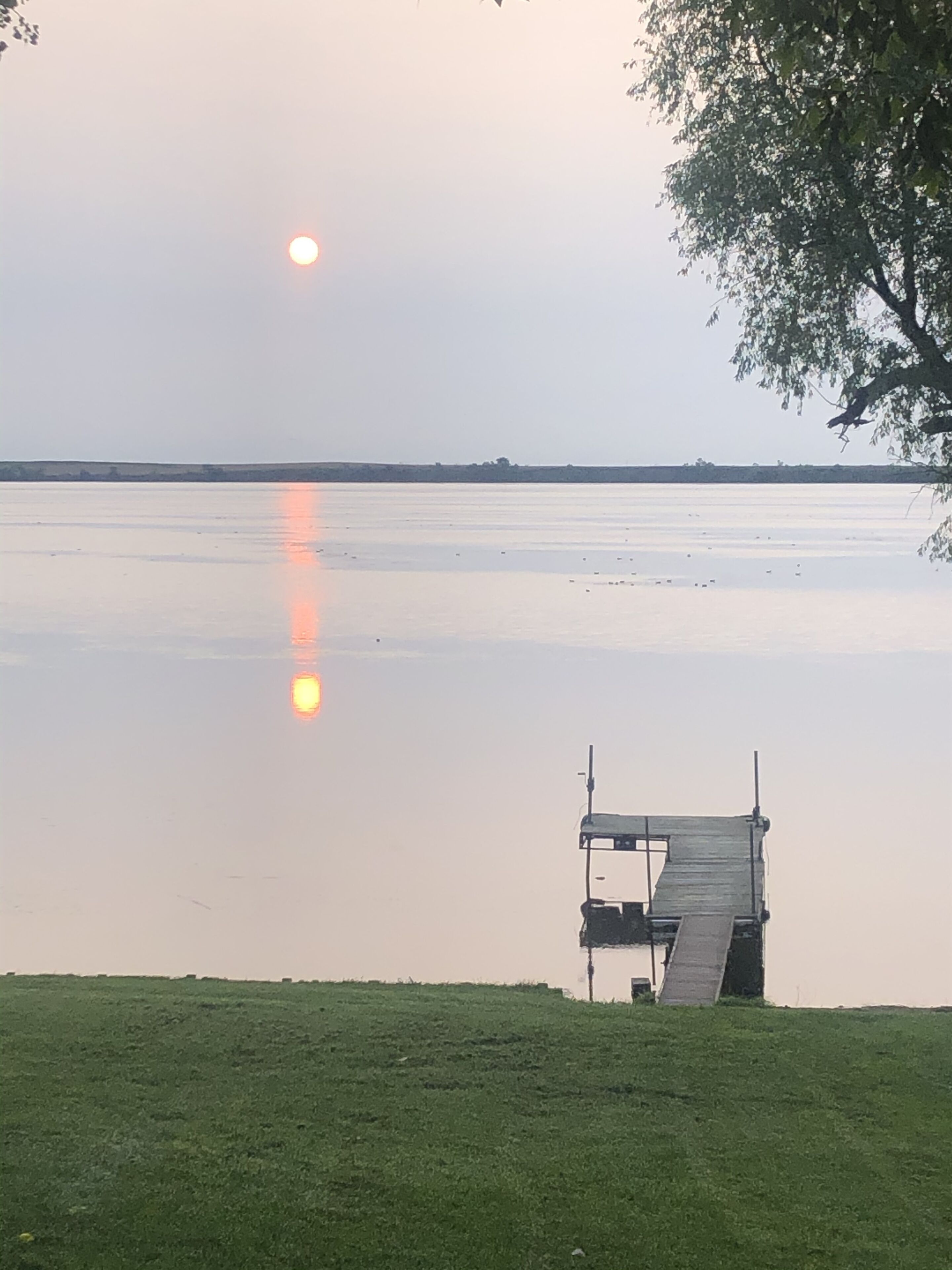 A calm lake with a wooden dock extending into the water.