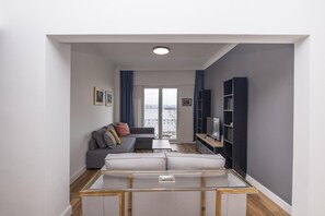 A modern living room with a sofa, a glass coffee table, and a TV stand.