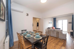 A dining area with a table set for four, a sofa, and a window with curtains.