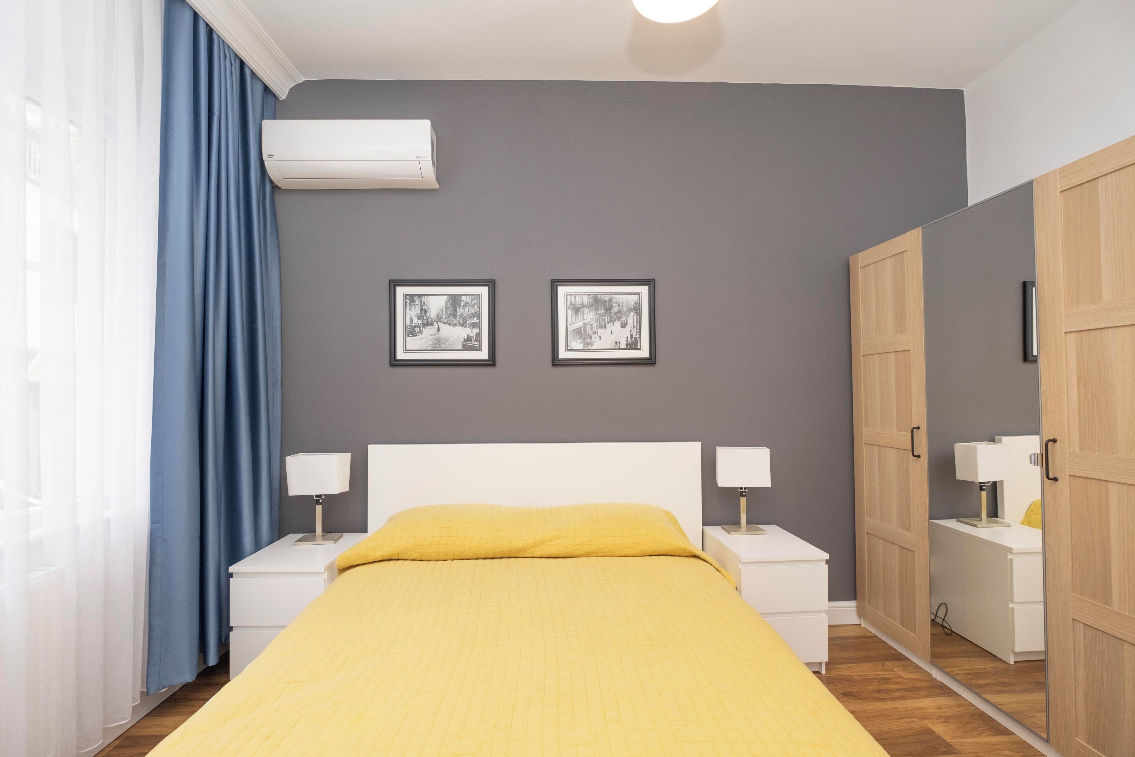 Une chambre à coucher comprenant un lit, des tables de chevet, une armoire et deux tableaux encadrés accrochés au mur.