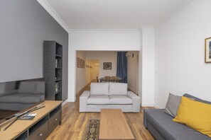 A modern living room with a grey sofa, a wooden coffee table, and a bookshelf.
