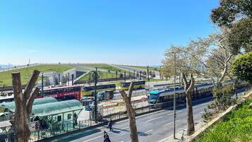 En busstation med flera bussar, ett övergångsställe och en gräsklädd kulle i bakgrunden.
