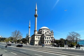 A large building with a prominent dome and two tall minarets, situated by a waterfront.