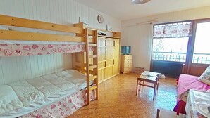 Una habitación con literas, un escritorio, una silla, un armario y una ventana con vistas.