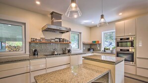 A modern kitchen with granite countertops, stainless steel appliances, and pendant lighting. - 'The Glabin’: Garrison Gem w/ Hot Tub & Fire Pit (Garrison)