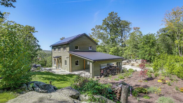 A two-story house with a covered porch, surrounded by a well-maintained garden and large rocks. - 'The Glabin’: Garrison Gem w/ Hot Tub & Fire Pit (Garrison)
