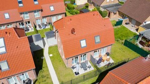 A residential building with a red-tiled roof, multiple windows, and a visible patio area with outdoor furniture.