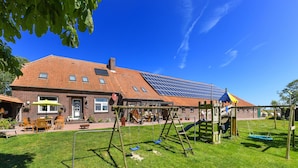 A residential building with a red-tiled roof, a brick facade, and a solar panel array. - Vacation apartment Gänseblümchen - Holiday apartments on the Schmidt farm (Paderborn)
