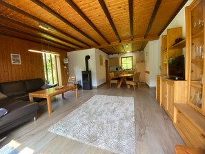 Un intérieur en bois comprenant un canapé, une table à manger et un coin cuisine.