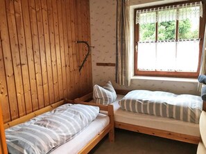 Une pièce avec deux lits superposés en bois, une fenêtre avec des rideaux et un mur en bois.