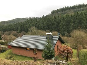 Un bâtiment d’un seul étage, construit en briques, avec un toit en pente, une antenne parabolique et une petite fenêtre.