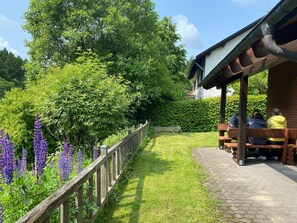 A covered outdoor seating area with a wooden fence and a paved path.