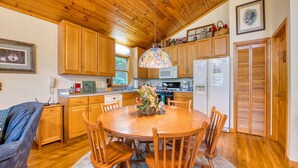 A wooden kitchen with a dining area, wooden cabinets, a refrigerator, and a stained glass light fixture.