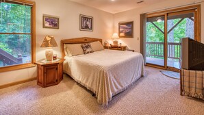 A bedroom with a bed, a nightstand, a lamp, and a ceiling fan. There are two windows and a door leading to a balcony.