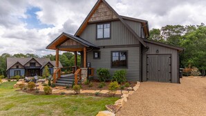 A two-story house with a covered porch, a stone staircase, and a gravel driveway.