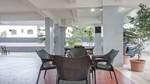 An outdoor seating area with wicker chairs and a table, surrounded by potted plants and a view of a street. - Treebo Diamond Residency - DDPK Inn (Pune)