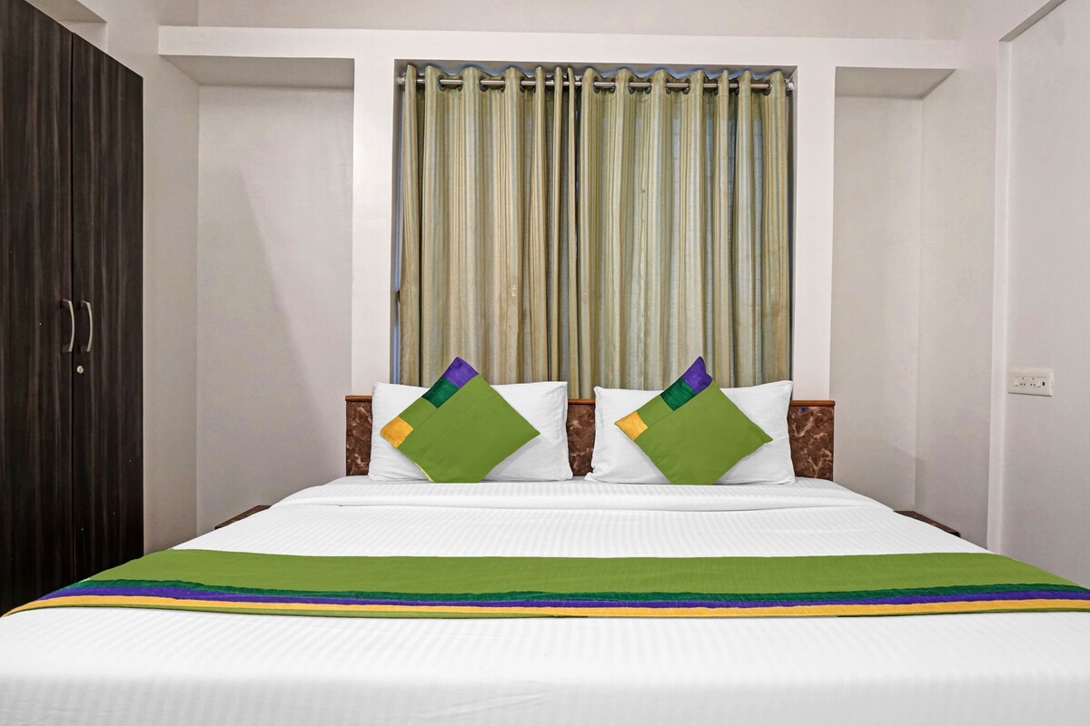 A hotel room with a bed, a curtain, and a wardrobe.