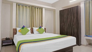 A hotel room with a bed, a nightstand, a wardrobe, and curtains. - Treebo Diamond Residency - DDPK Inn (Pune)