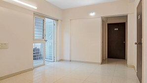 A hallway with a sliding glass door leading to a balcony, a dark door labeled "202-", and a light switch on the wall. - Treebo Diamond Residency - DDPK Inn (Pune)