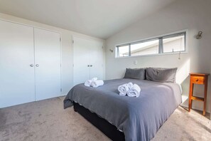 Ein Schlafzimmer mit einem großen Bett, einem Kleiderschrank, einem Fenster und einem Nachttisch.
