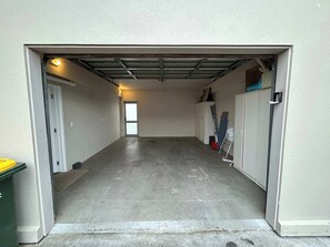 Eine Garage mit Betonboden, einer weißen Tür und einer Metallrolltür.