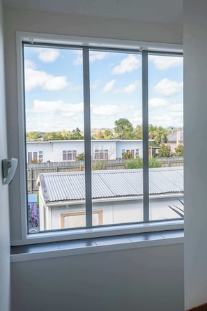 A window with a view of residential buildings and a clear sky.
