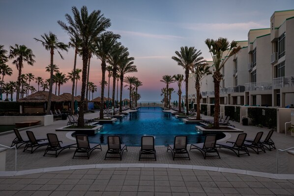 Relax by the pool surrounded by palm trees and buildings with balconies.