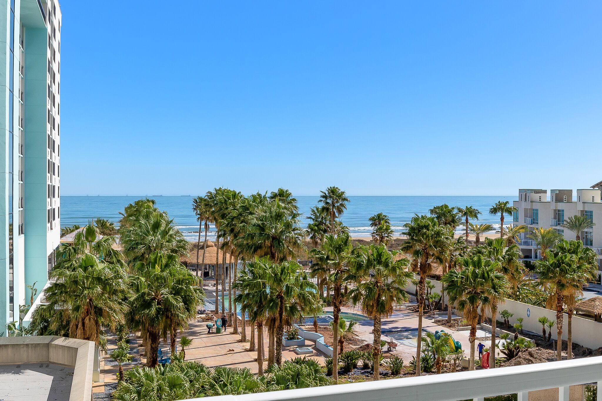 Ein Strandhotel mit Palmen, einem Poolbereich und Blick auf den Ozean.