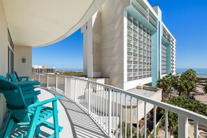 Enjoy the ocean view from this hotel's balcony, featuring comfortable chairs and a railing.
