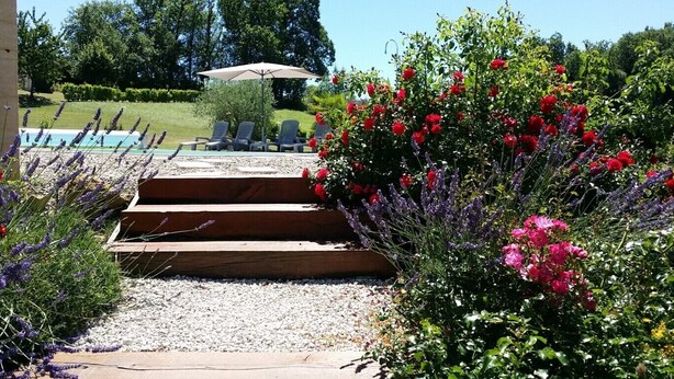 A garden pathway leading to a pool area with outdoor seating and a wooden deck. - Sarlajoande, a modern villa in Perigord style (Proissans)