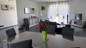 A modern living room with a dining area, a sofa, a TV, and a cabinet. - Sarlajoande, a modern villa in Perigord style (Proissans)