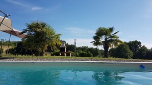 A swimming pool with clear blue water, surrounded by palm trees and a gazebo. - Sarlajoande, a modern villa in Perigord style (Proissans)
