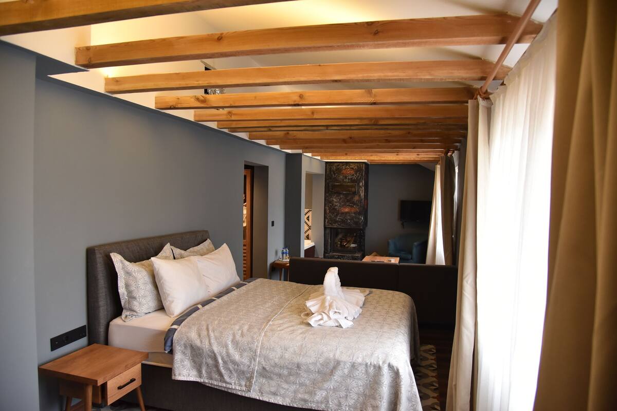 A bedroom with a bed, nightstand, and a wooden ceiling structure.