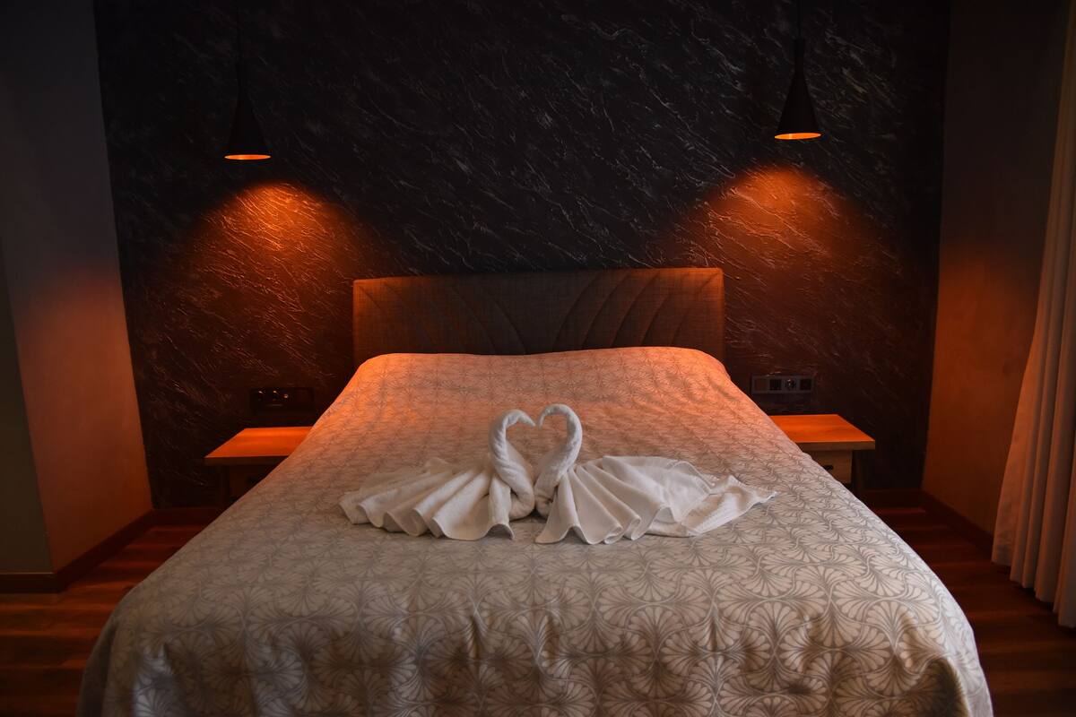 A hotel room with a bed, two bedside tables, and a marble-patterned wall.