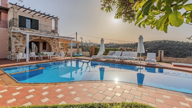 Un espace piscine avec des chaises longues et un bâtiment en pierre doté d’un balcon.