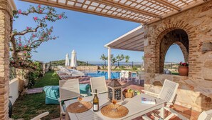 Un espace aménagé au bord de la piscine, avec des chaises longues, une table où sont servis des boissons et une vue sur la mer.