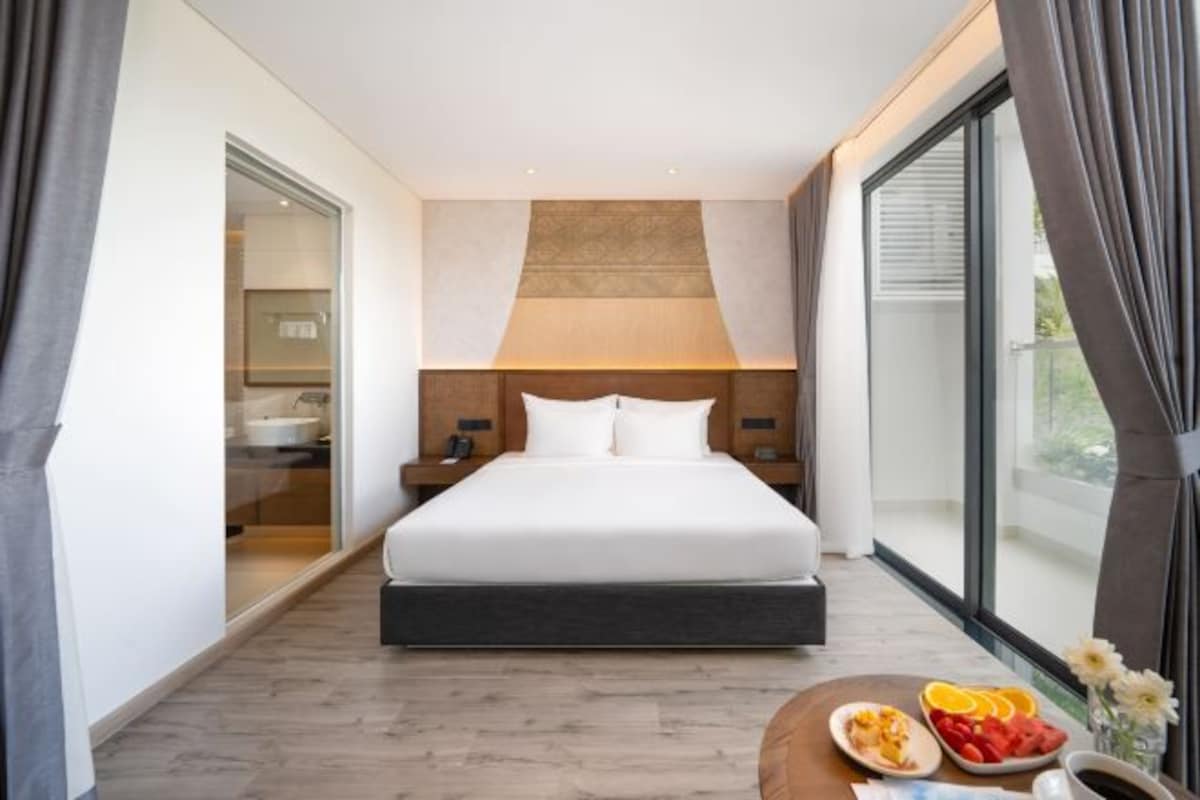 Una habitación de hotel moderna con una cama grande, una mesita de noche y cortinas en la ventana, con vistas al exterior.