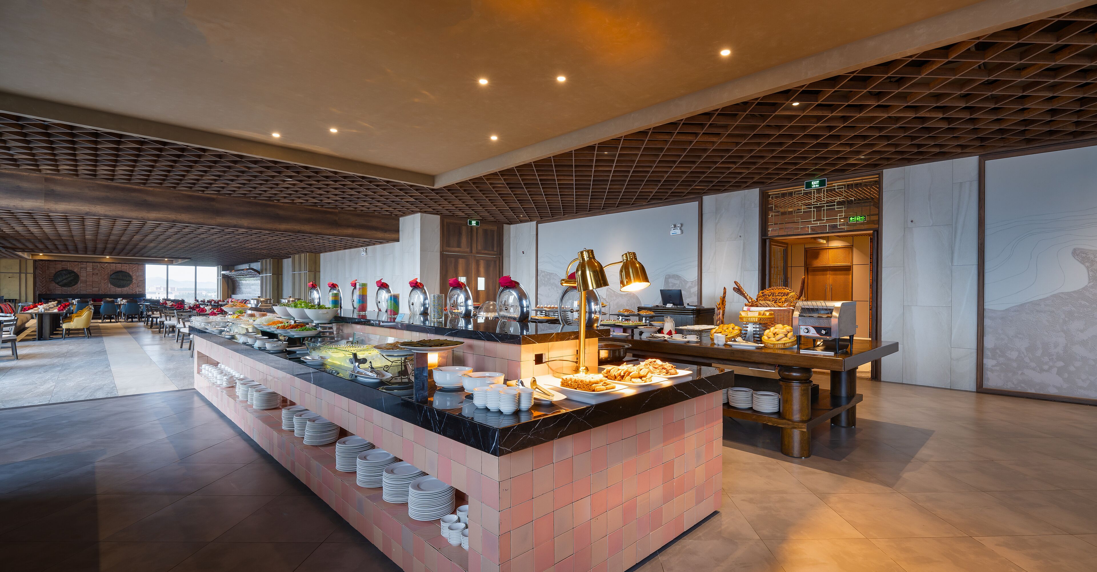 A buffet area with multiple food stations, a seating area with chairs, and a modern ceiling design.