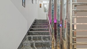 A marble staircase leading to a room with a glass partition and a framed picture on the wall. - Treebo Sidhartha Elite (Bhubaneshwar)