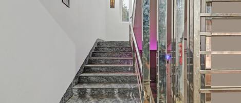 A marble staircase leading to a room with a glass partition and a framed picture on the wall.