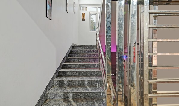 A marble staircase leading to a room with a glass partition and a framed picture on the wall. - Treebo Sidhartha Elite (Bhubaneshwar)