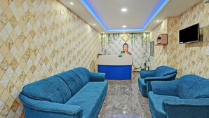 A reception area with a blue sofa, a reception desk, and a Buddha statue. - Treebo Sidhartha Elite (Bhubaneshwar)