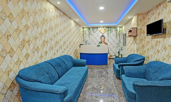 Un área de recepción con un sofá azul, un mostrador de recepción y una estatua de Buda.