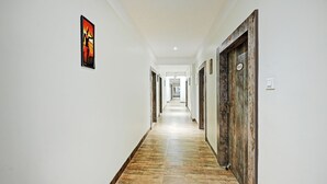 A long, narrow hallway with white walls and a wooden floor. There are doors on both sides, some with numbers on them. - Treebo Sidhartha Elite (Bhubaneshwar)
