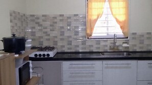 A kitchen with a gas stove, a sink, and a window with curtains. - 3 Bed House - Sleeps 4 - Parking - Enclosed Garden (Paramaribo)