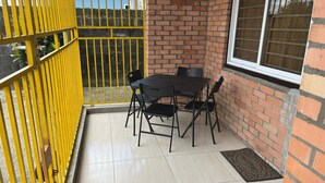 A small patio area with a table and chairs, a yellow gate, and a brick wall. - 3 Bed House - Sleeps 4 - Parking - Enclosed Garden (Paramaribo)
